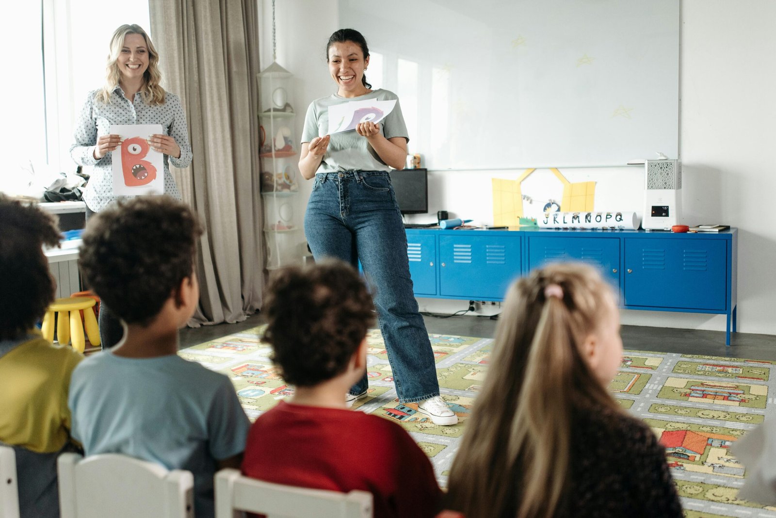 A teacher presenting educational flashcards to a classroom of young children during an interactive learning session in a modern primary school classroom.